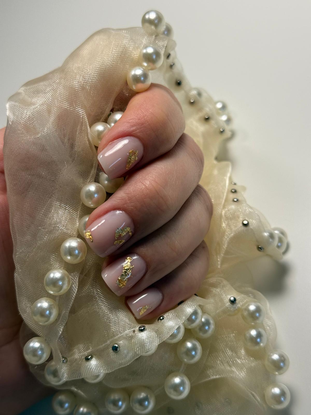 Gainage sur ongles naturels rose avec décor de feuille d’or, sur le barp